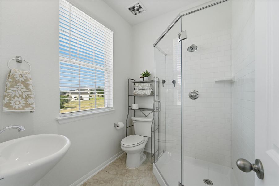 A pristine bath featuring a glass-enclosed shower and bright window. A pristine bath featuring a glass-enclosed shower and bright window.