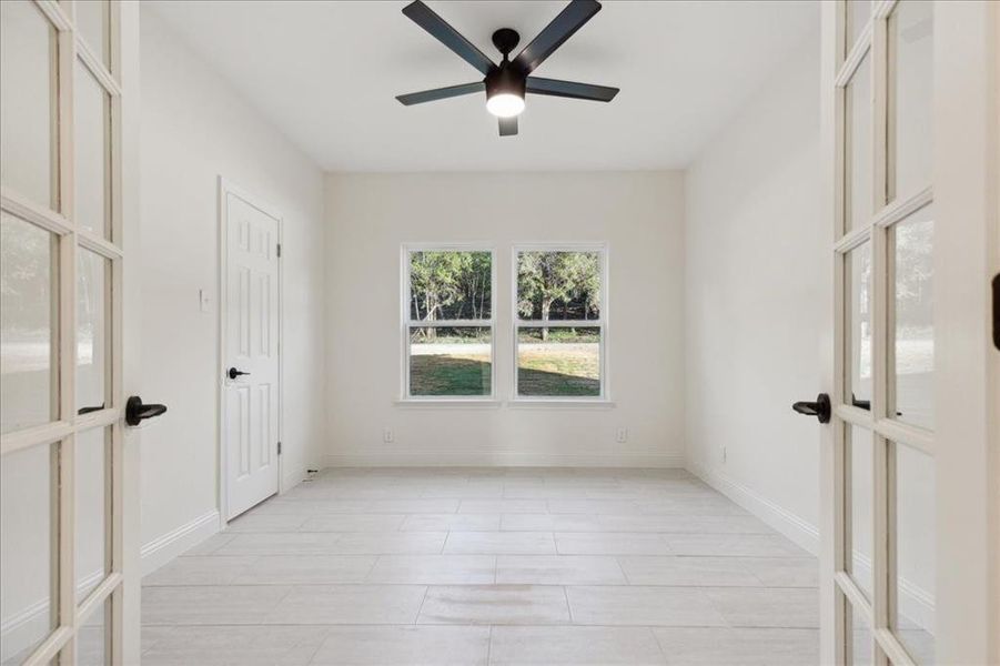 Empty room featuring ceiling fan and french doors