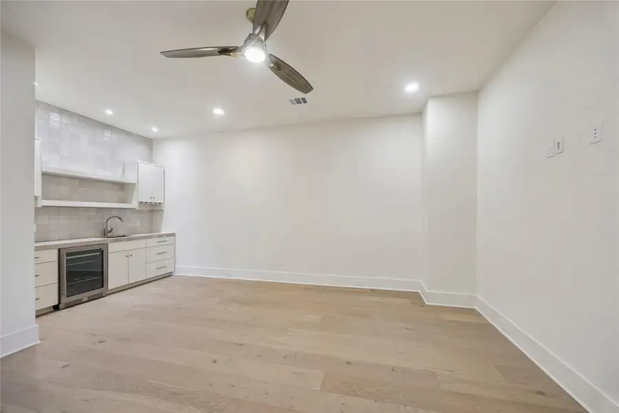 MEDIA ROOM/FLEX SPACE: Dedicated media room/flex area features a built-in wet bar with sink, Mont Blanc Gold Quartzite countertops, and designer Spark Ivory Matte wall tile.
