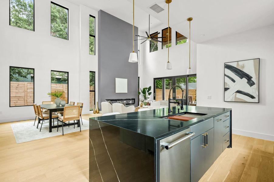 A modern open-concept living area with a dramatic two-story ceiling and sleek kitchen island. A modern open-concept living area with a dramatic two-story ceiling and sleek kitchen island.