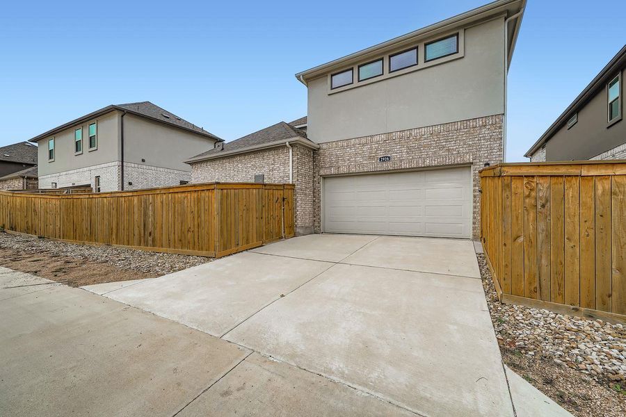 View of front of property with brick siding, an attached garage, driveway, and stucco siding View of front of property with brick siding, an attached garage, driveway, and stucco siding
