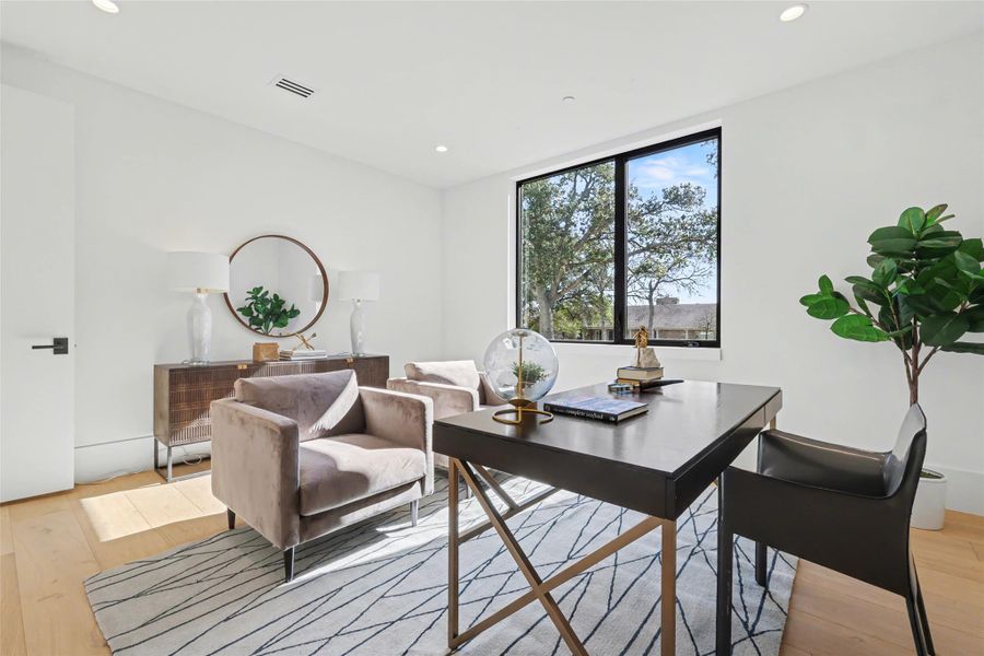 Home office with light wood-style floors and recessed lighting