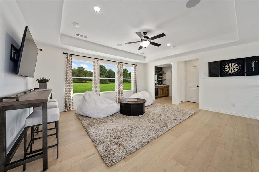 Game room featuring light hardwood / wood-style flooring, ceiling fan, and a raised ceiling