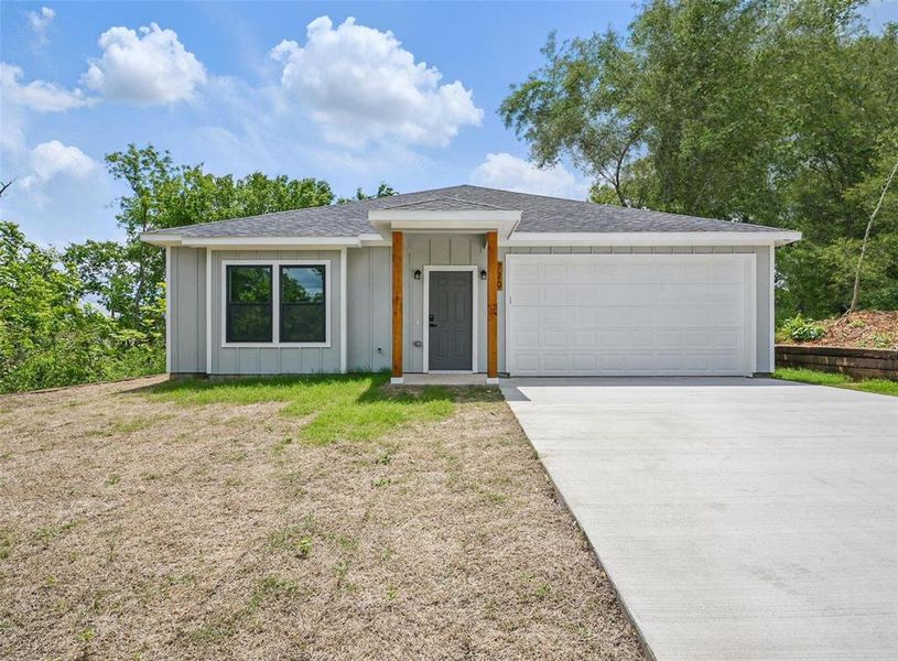 View of front of home featuring board and batten siding, driveway, an attached garage, and roof with shingles