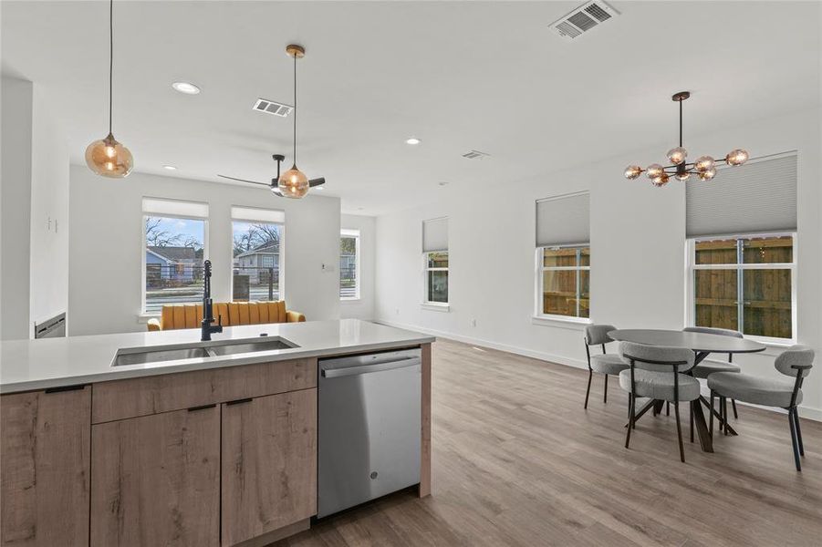 Kitchen featuring dishwasher, sink, hanging light fixtures, light hardwood / wood-style flooring, and a chandelier