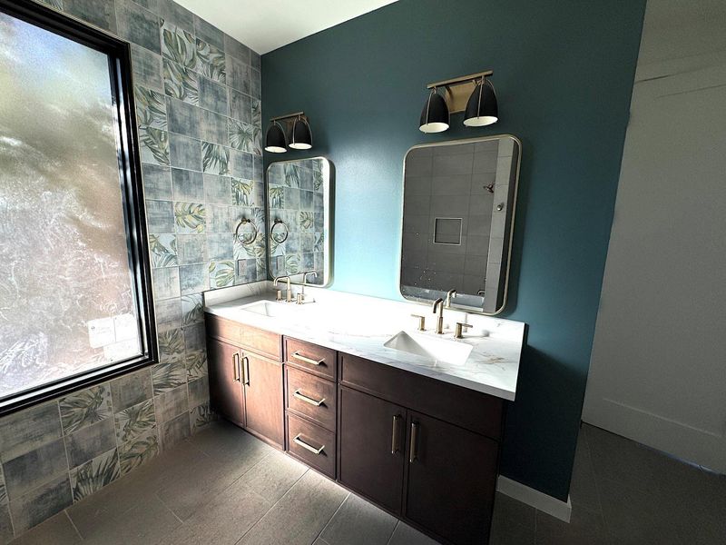 Full bathroom featuring a sink, tile walls, double vanity, and a tile shower