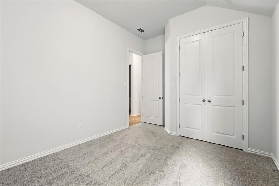 Unfurnished bedroom featuring light carpet and a closet
