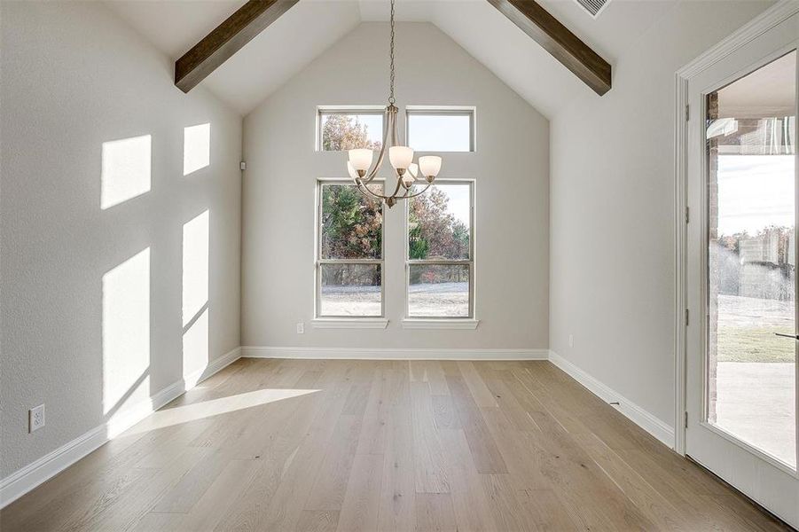 Unfurnished dining area with beamed ceiling, light hardwood / wood-style floors, high vaulted ceiling, and an inviting chandelier