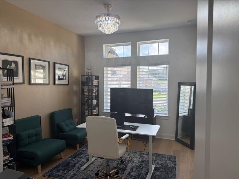 Utilize this 4th bedroom as an inviting office space with large windows, elegant chandelier, and stylish decor, perfect for productivity and comfort.