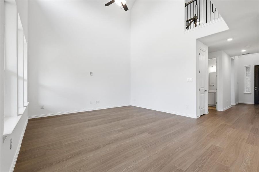 Empty room with light wood-type flooring, a ceiling fan, recessed lighting, and a high ceiling
