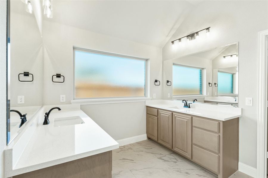 Master bathroom with dual vanities, white quartz countertops, tan cabinets, and marble tile floors Master bathroom with dual vanities, white quartz countertops, tan cabinets, and marble tile floors