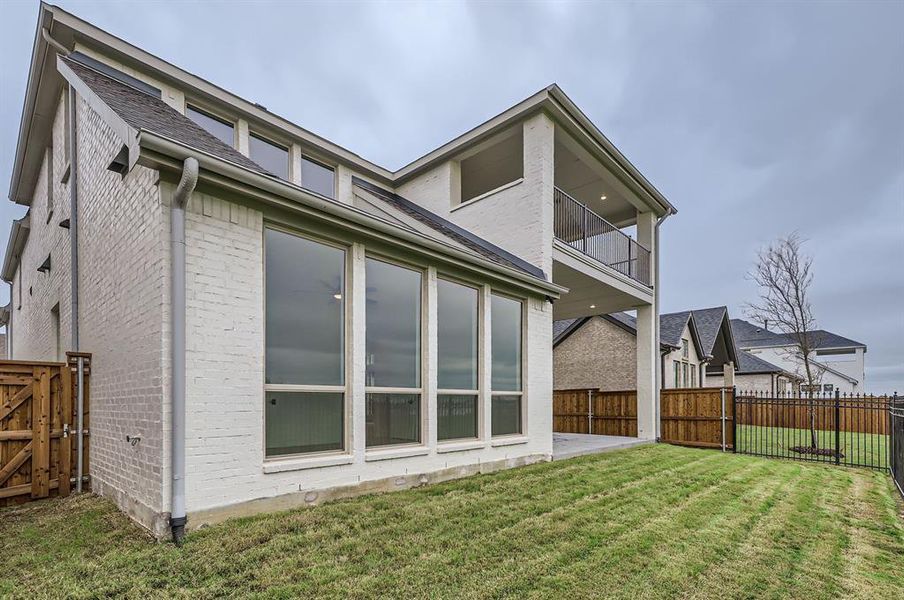 Back of house featuring a balcony and a yard