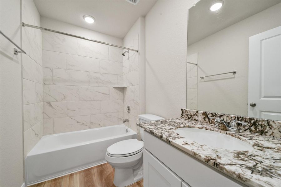 Sophisticated modern bathroom featuring elegant marble-patterned tile and a striking granite vanity for a perfect blend of style and function.