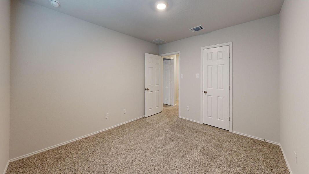 Unfurnished bedroom with light colored carpet and baseboards