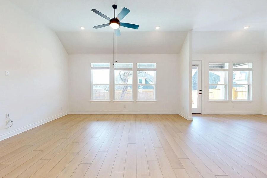The open living space features light-toned wood flooring, a ceiling fan with integrated lighting, and recessed lighting