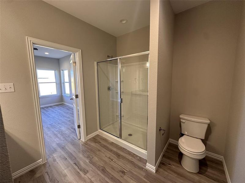 Bathroom with hardwood / wood-style floors, toilet, and walk in shower