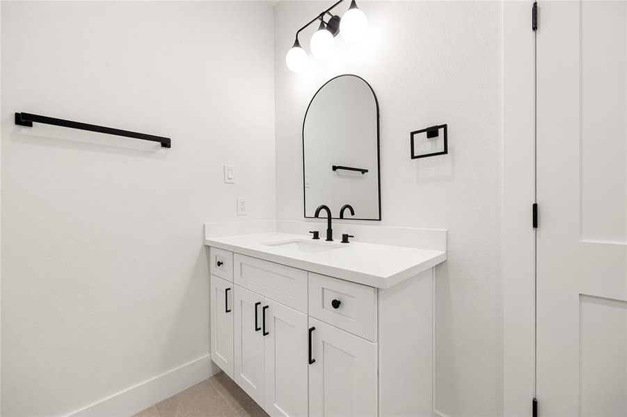 Sleek & Modern Vanity SpaceThis stylish vanity area features a quartz countertop, black fixtures, and ample storage. The arched mirror and contemporary lighting add a touch of elegance to this bright and functional space!