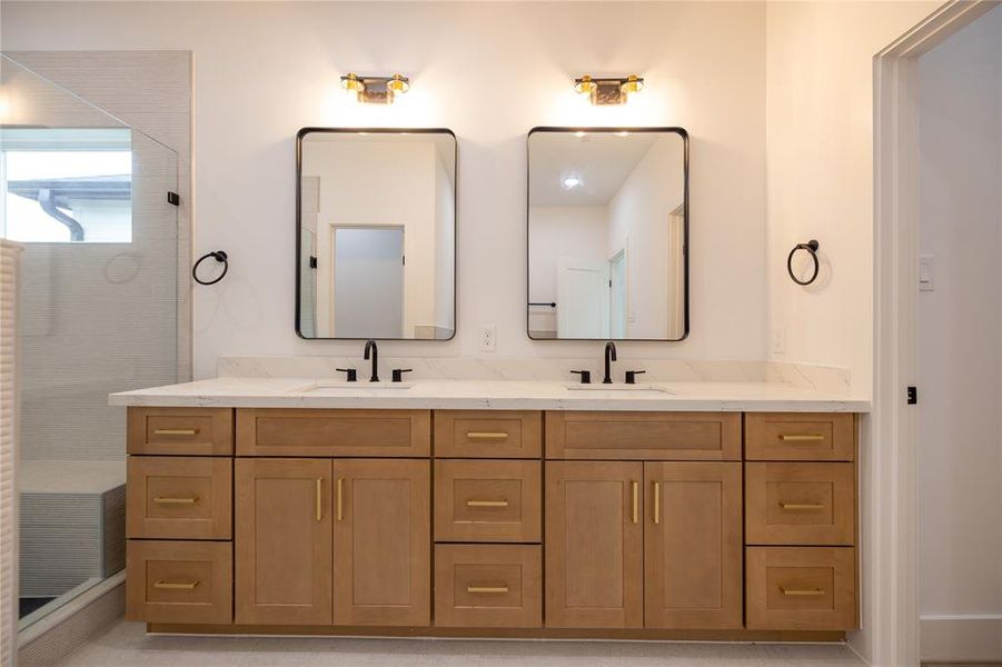 Primary bathroom offers a spacious dual vanity with under-mount sinks, and black faucets. Thoughtfully laid out cabinetry combines drawers with cabinets to leave no space wasted.