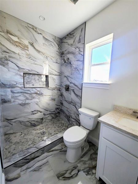 Bathroom with toilet, vanity, and a tile shower