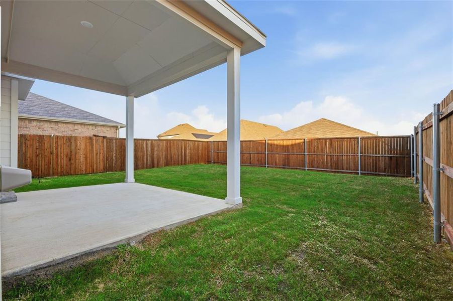 Covered patio with a concrete slab, expansive grassy yard, and full privacy fencing Covered patio with a concrete slab, expansive grassy yard, and full privacy fencing