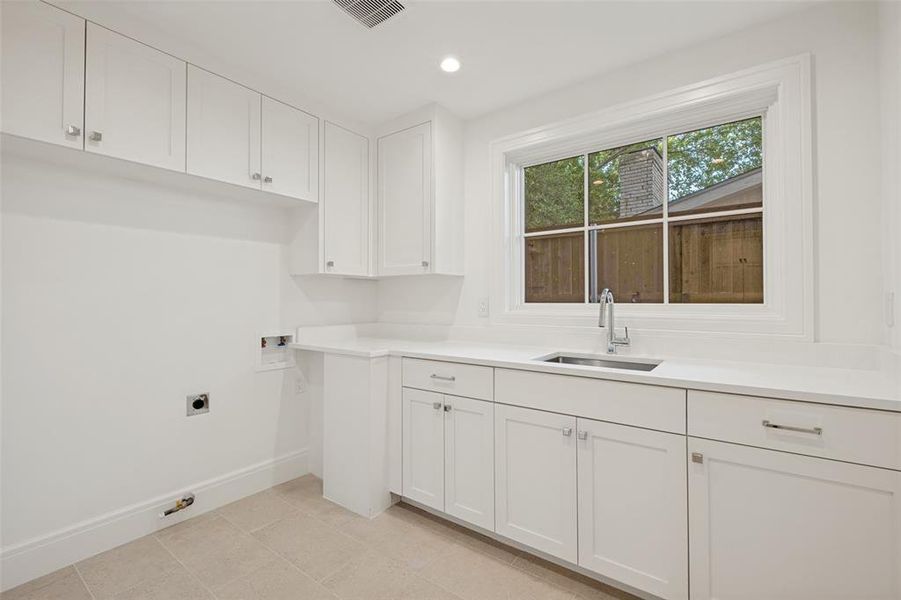 Spacious first-floor laundry room featuring a utility sink and abundant storage space. Spacious first-floor laundry room featuring a utility sink and abundant storage space.