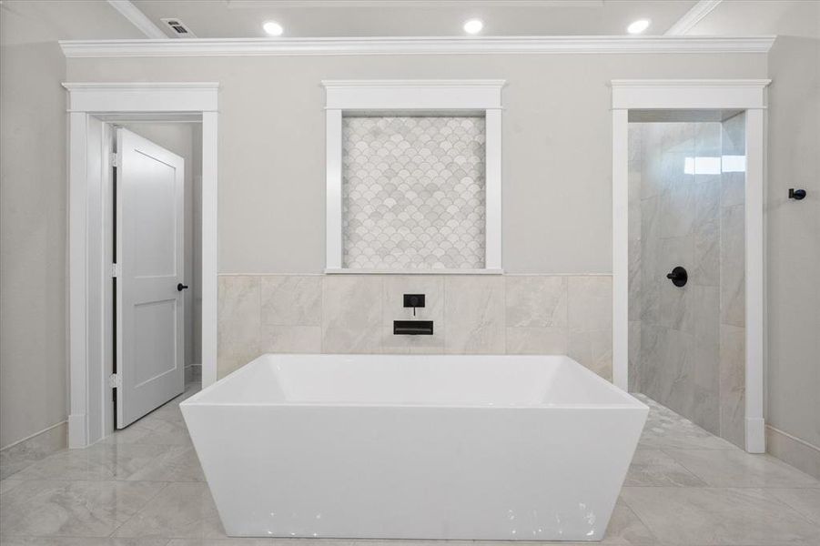 Bathroom with a bath, tile walls, and ornamental molding