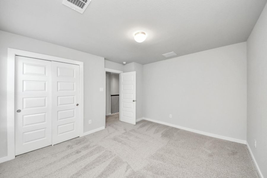 Secondary bedroom features plush carpeting, large windows that let in plenty of natural light, bright paint, and spacious closets. Sample photo of completed home with similar floor plan. Actual colors and selections may vary.