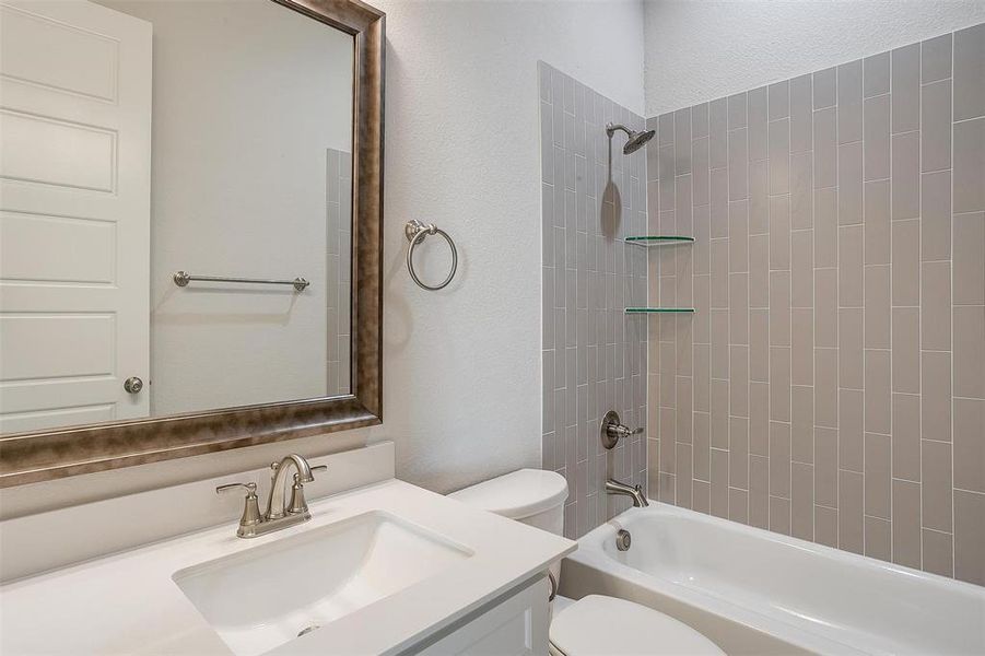 Full bathroom with vanity, tiled shower / bath combo, and toilet