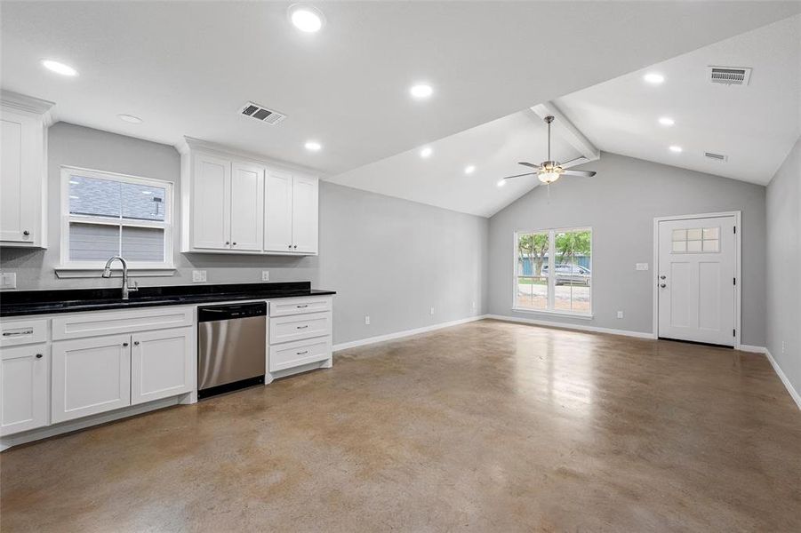 Kitchen with baseboards, visible vents, concrete flooring, and dishwasher
