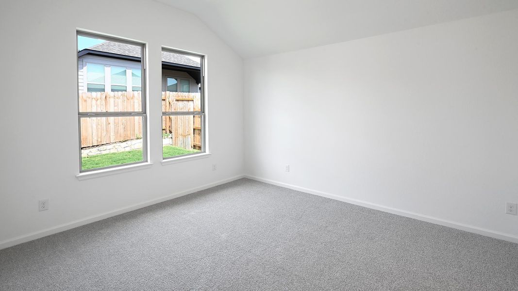 Carpeted empty room with lofted ceiling and baseboards Carpeted empty room with lofted ceiling and baseboards