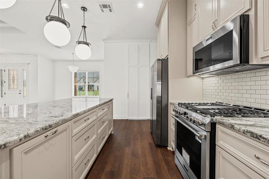 Kitchen with appliances with stainless steel finishes, decorative backsplash, dark wood-type flooring, recessed lighting, and light stone counters Kitchen with appliances with stainless steel finishes, decorative backsplash, dark wood-type flooring, recessed lighting, and light stone counters