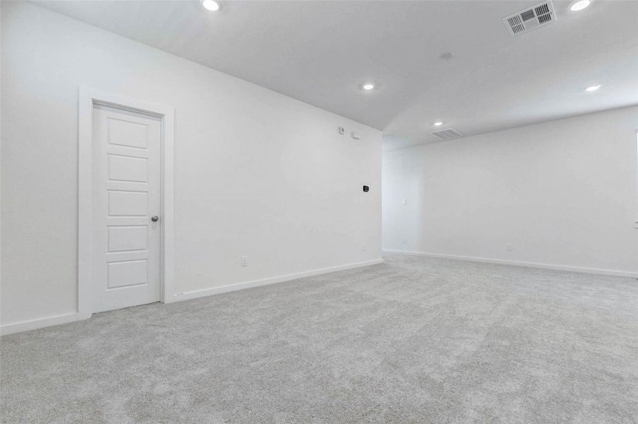 Expansive living area with neutral carpet, bright white walls, recessed lighting, and an open layout that connects easily to the kitchen and entry spaces. This blank-slate room offers generous space for seating, media, décor, and everyday relaxation.