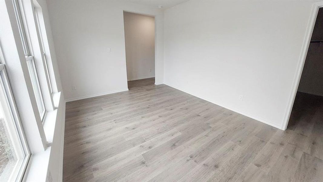 Unfurnished bedroom with light wood finished floors and a walk in closet Unfurnished bedroom with light wood finished floors and a walk in closet