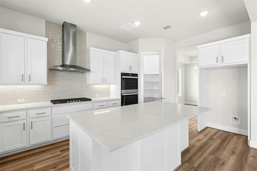 Kitchen with decorative backsplash, a center island, light stone countertops, white cabinetry, and recessed lighting