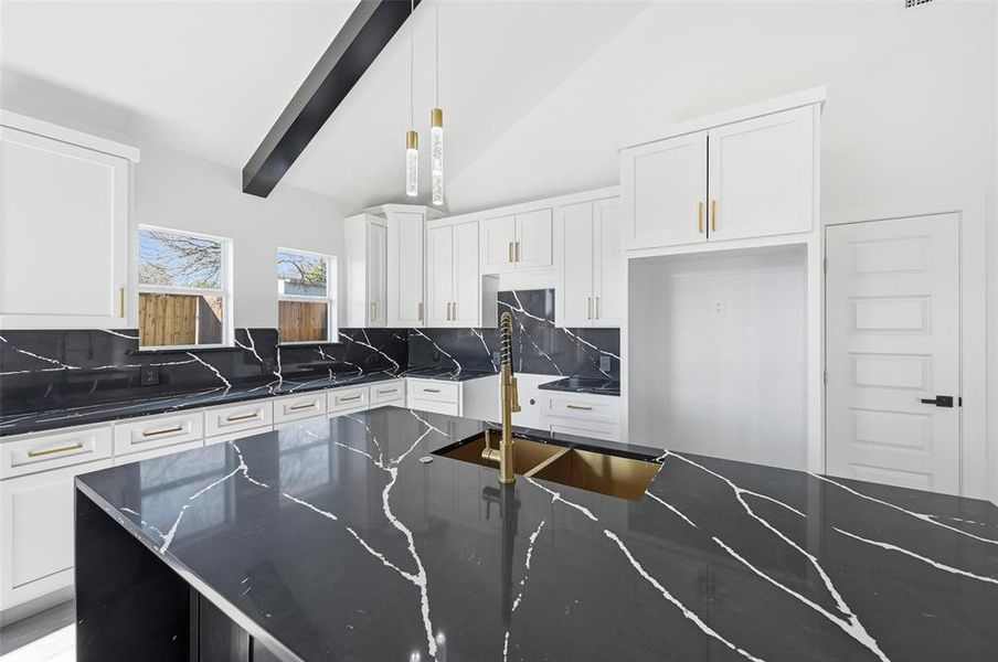Kitchen featuring white cabinets, hanging light fixtures, decorative backsplash, dark stone countertops, and high vaulted ceiling Kitchen featuring white cabinets, hanging light fixtures, decorative backsplash, dark stone countertops, and high vaulted ceiling