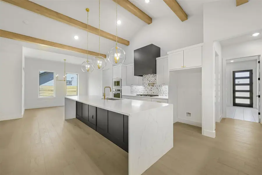Kitchen featuring recessed lighting, beamed ceiling, white cabinetry, light wood finished floors, and a spacious island