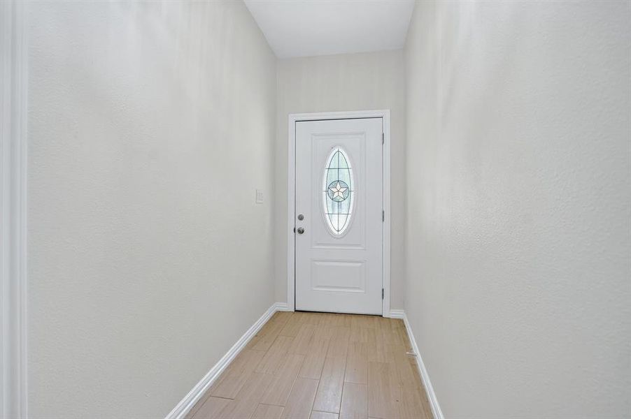 Entryway with wood-finish flooring, white baseboards, and light-toned walls