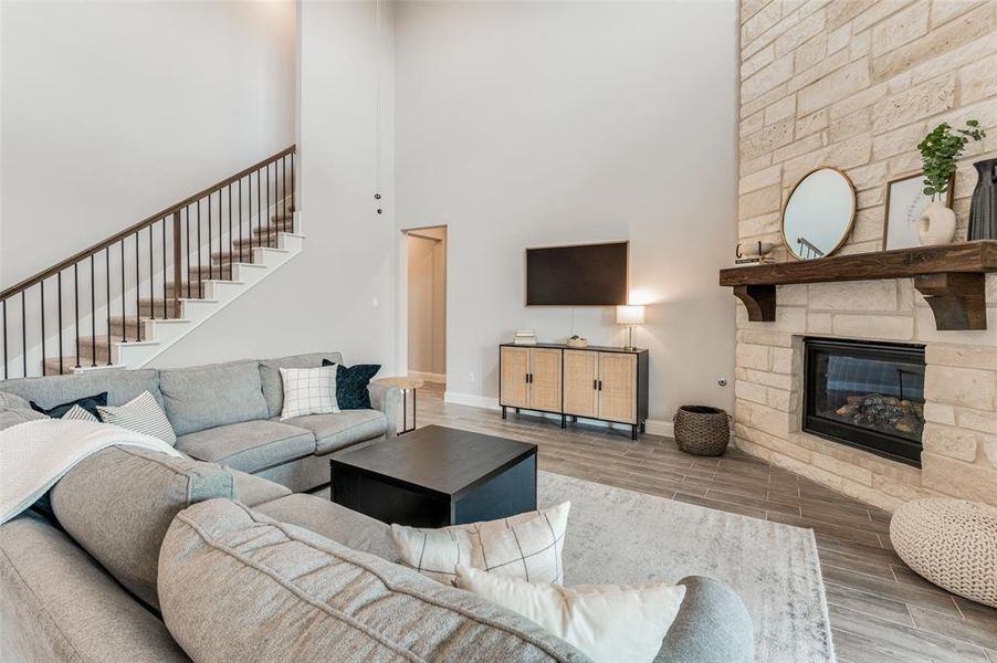 Living room with a fireplace, hardwood / wood-style flooring, and a towering ceiling