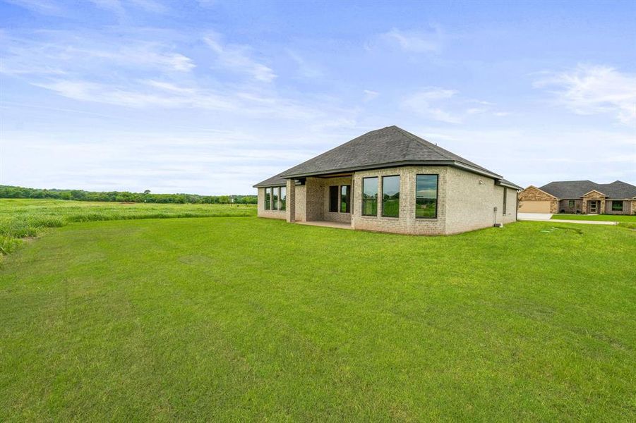 Rear view of house featuring a lawn and brick siding
