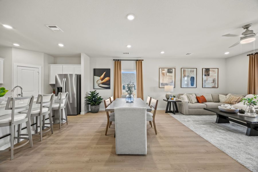 A large living room with a wood floor and a large dining table.