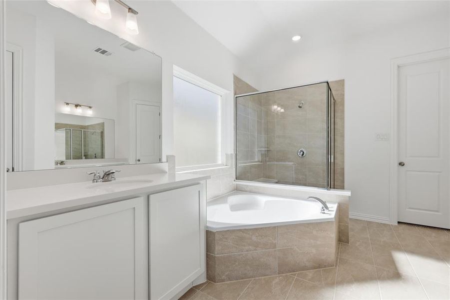 Bathroom featuring vanity, a shower stall, a garden tub, and light tile patterned floors