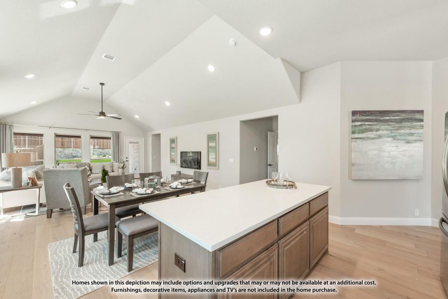 Open-concept kitchen with large island, vaulted ceiling, and dining area with hardwood floors Open-concept kitchen with large island, vaulted ceiling, and dining area with hardwood floors