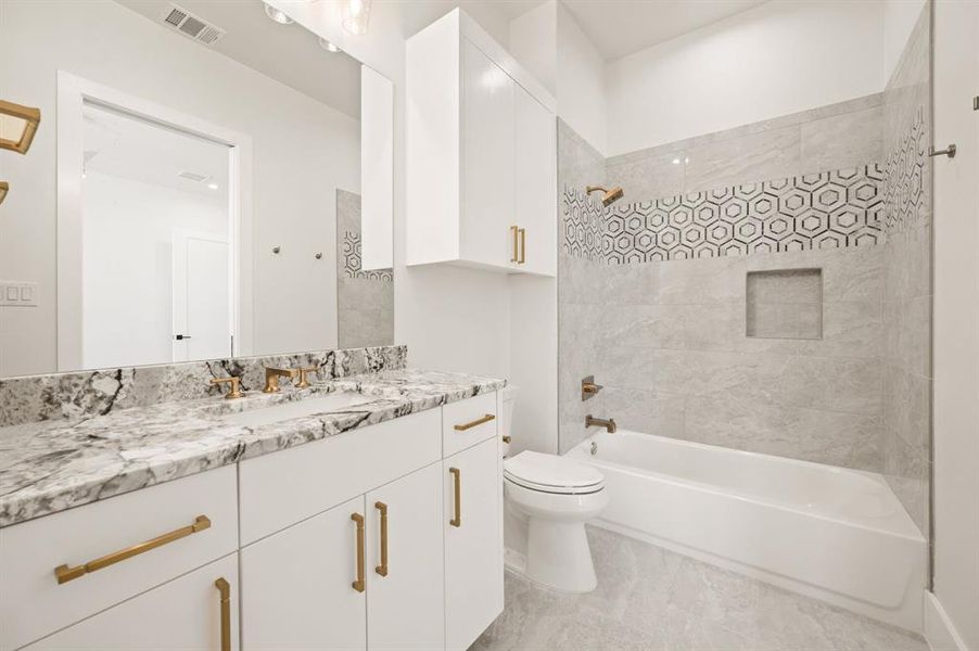 Full bathroom with tiled shower / bath, vanity, and toilet