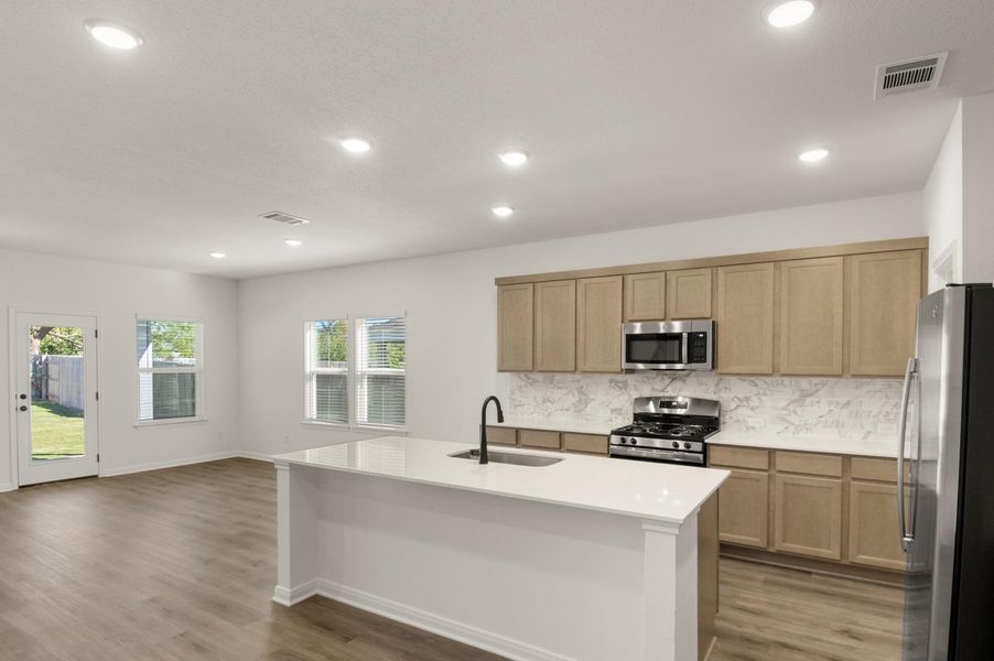 Kitchen with decorative backsplash, stainless steel appliances, dark wood-style floors, a kitchen island with sink, and recessed lighting Kitchen with decorative backsplash, stainless steel appliances, dark wood-style floors, a kitchen island with sink, and recessed lighting