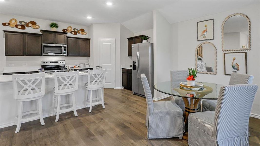 Kitchen featuring dark wood finish cabinetry, stainless steel appliances, dark wood-style flooring, a kitchen bar, and recessed lighting Kitchen featuring dark wood finish cabinetry, stainless steel appliances, dark wood-style flooring, a kitchen bar, and recessed lighting