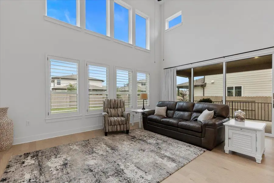 Living area with light wood finished floors, healthy amount of natural light, and a high ceiling