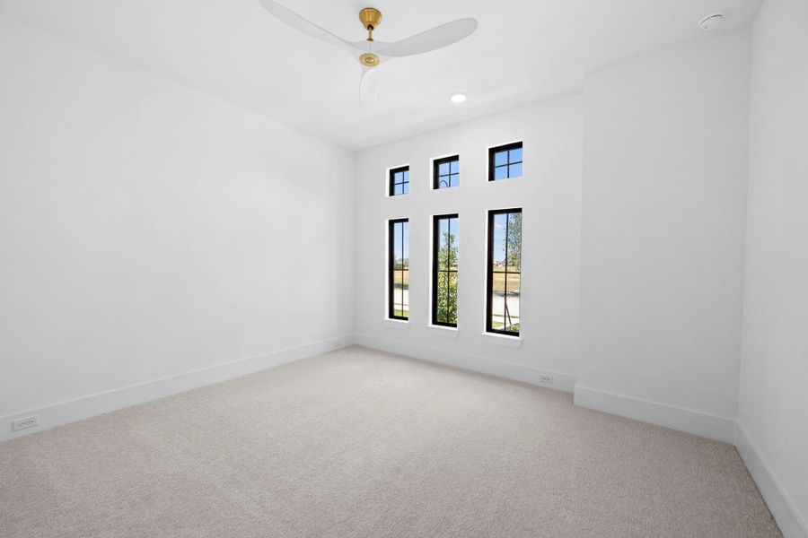 Spacious bedroom featuring soaring ceilings, large windows, and a bright, airy atmosphere.
