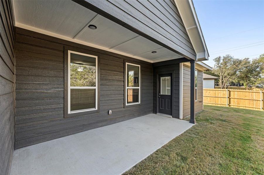 Doorway to property with a patio area and a lawn