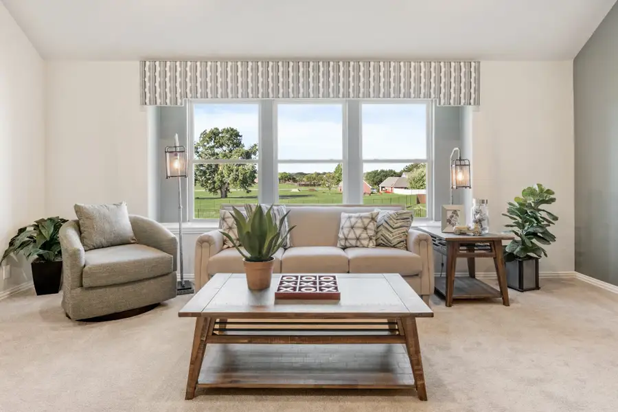 Living room with beige sofa, wood coffee table, and large window overlooking a green lawn and lake view