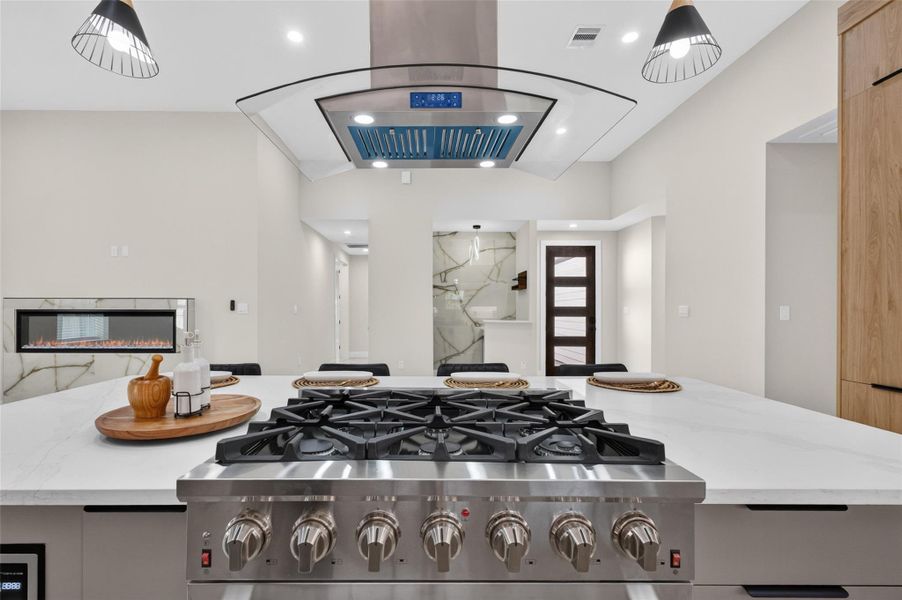 Modern kitchen featuring a sleek gas range, spacious island with elegant lighting, and a stylish open layout perfect for entertaining.